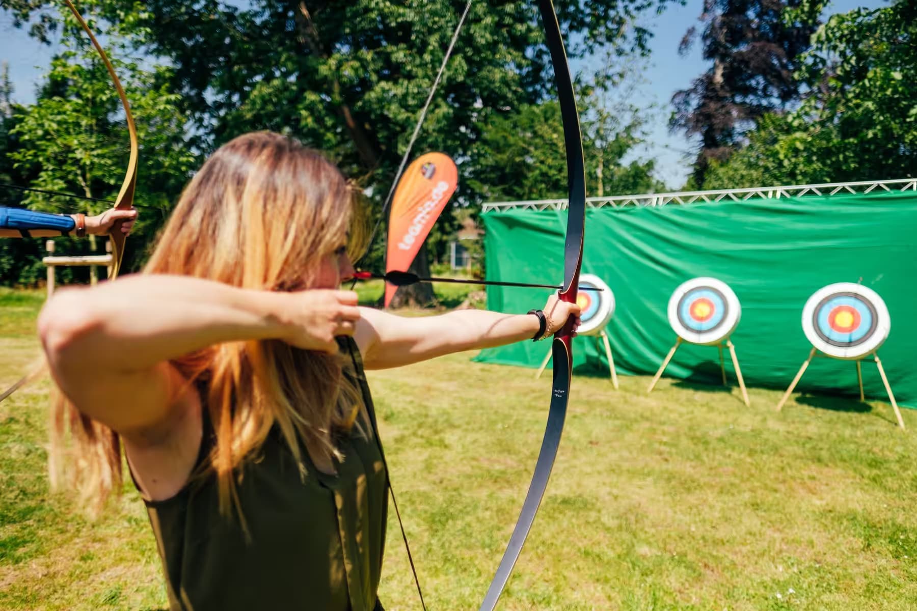 Coach gibt Einweisung beim Bogenschießen für Gruppen